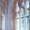 Old arched Catholic church corridor with white walls and with stained glass window in daylight